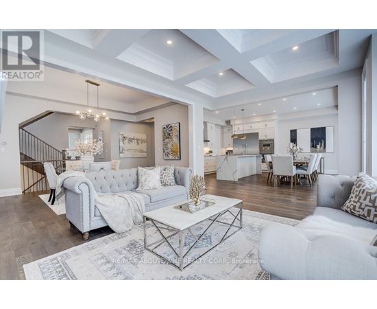 A spacious living room with a white sofa set and a chandelier.