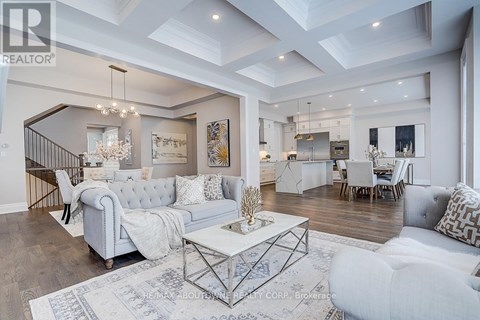 A spacious living room with a white sofa set and a chandelier.