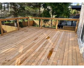 A wooden deck with a railing and trees in the background.