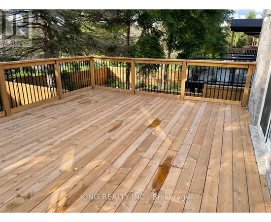 A wooden deck with a railing and trees in the background.