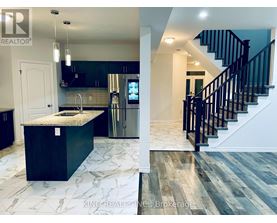 A kitchen with a marble countertop and a staircase with black railings.