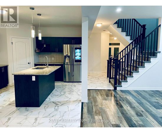 A kitchen with a marble countertop and a staircase with black railings.