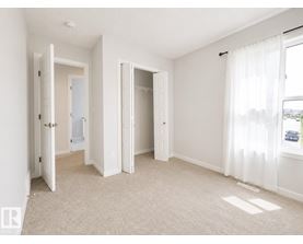 A white bedroom with a carpeted floor and two open doors.