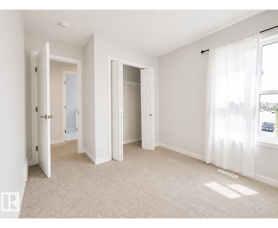A white bedroom with a carpeted floor and two open doors.