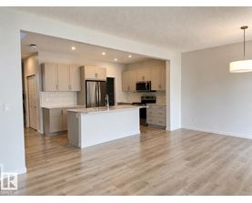 A kitchen with a white island and wooden floors.
