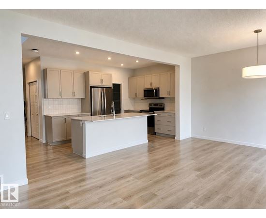 A kitchen with a white island and wooden floors.