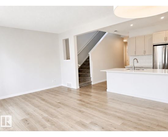A spacious kitchen with a refrigerator, sink, and cabinets.