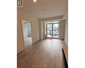 A room with wooden flooring and a sliding glass door leading to a balcony.