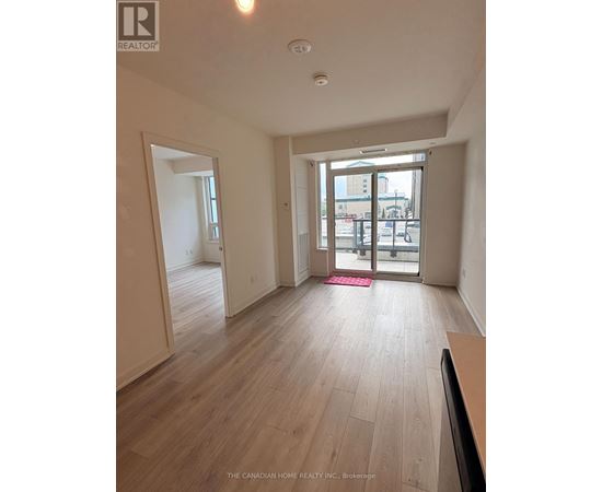 A room with wooden flooring and a sliding glass door leading to a balcony.