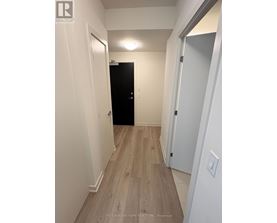 A hallway with a black door and white walls.