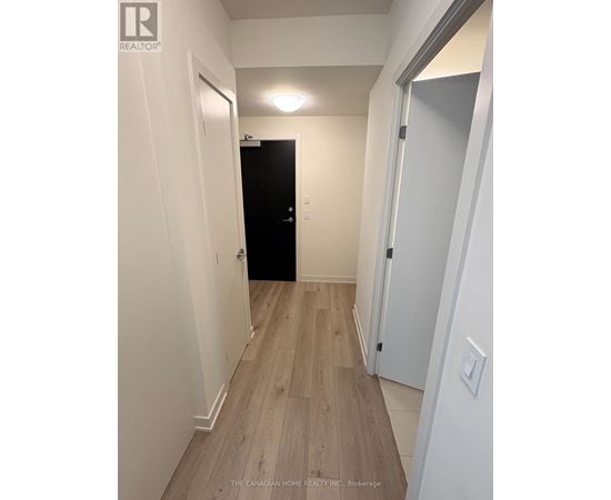 A hallway with a black door and white walls.