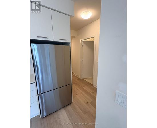 A kitchen with a stainless steel refrigerator and wooden floors.