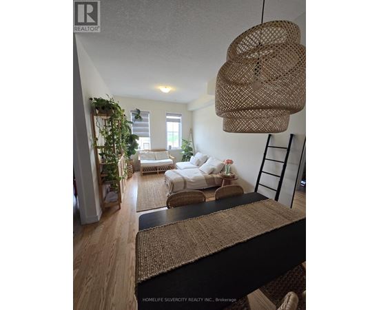 A living room with a white couch and a woven hanging light fixture.