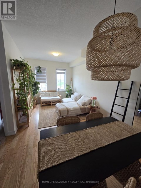 A living room with a white couch and a woven hanging light fixture.