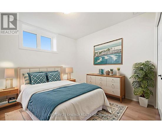 A bedroom with a bed, nightstand, and a painting on the wall.