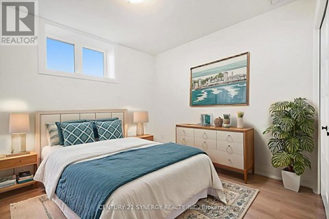 A bedroom with a bed, nightstand, and a painting on the wall.