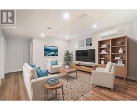 A living room with a white couch, a wooden coffee table, a flat screen TV, and a wooden entertainment center.