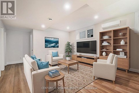 A living room with a white couch, a wooden coffee table, a flat screen TV, and a wooden entertainment center.