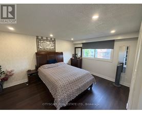 A bedroom with a bed, nightstand, and a wall hanging.