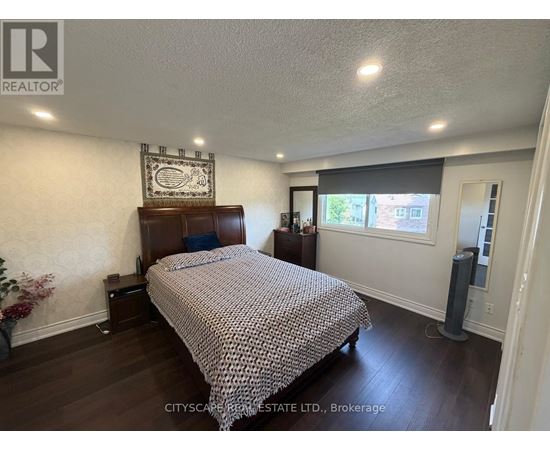 A bedroom with a bed, nightstand, and a wall hanging.