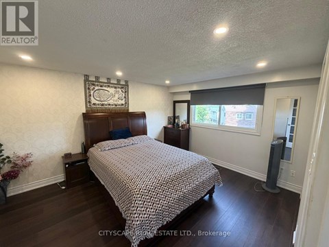 A bedroom with a bed, nightstand, and a wall hanging.