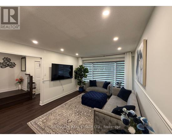 A living room with a grey couch and a television on the wall.