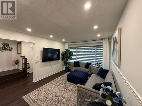 A living room with a grey couch and a television on the wall.
