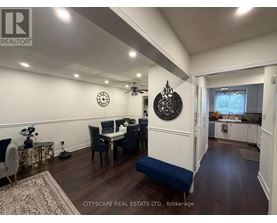 A dining room with a table set for four and a kitchen area in the background.
