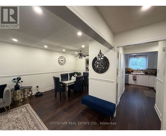 A dining room with a table set for four and a kitchen area in the background.
