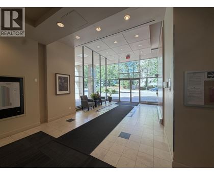 A hallway with a black carpet and a glass door leading to a balcony.