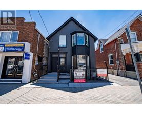 A black house with a realtor sign in front.