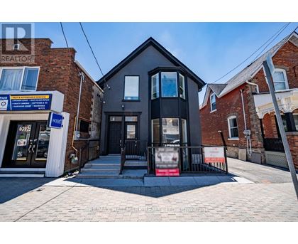A black house with a realtor sign in front.