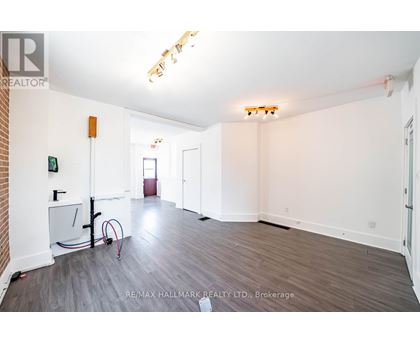 A spacious room with a brick wall and wooden flooring.