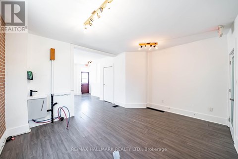 A spacious room with a brick wall and wooden flooring.
