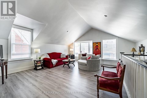 A living room with a red couch and a wooden floor.