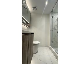 A bathroom with a toilet, sink, and a glass shower door.