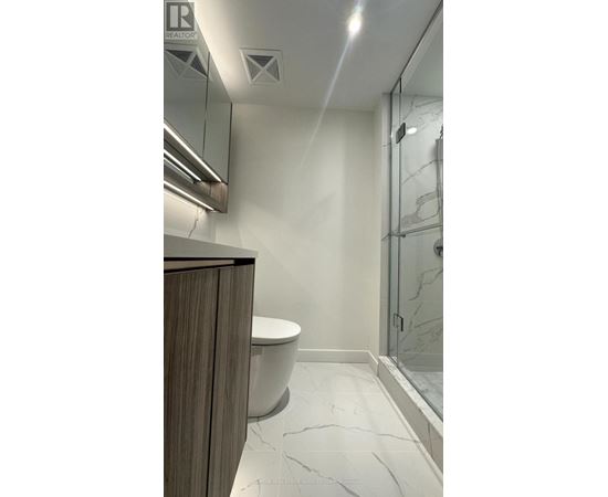 A bathroom with a toilet, sink, and a glass shower door.