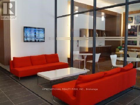 A living room with a red couch and a television mounted on the wall.