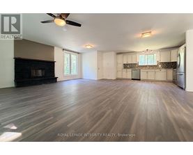 A spacious room with wooden flooring and a ceiling fan.