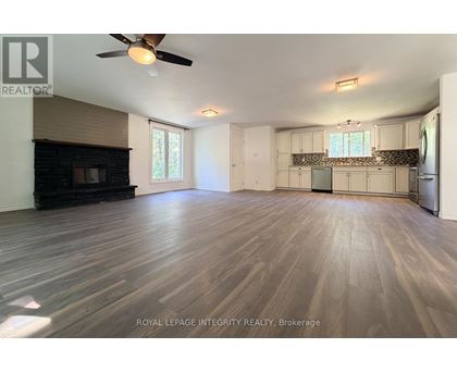 A spacious room with wooden flooring and a ceiling fan.