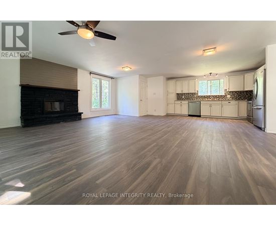 A spacious room with wooden flooring and a ceiling fan.