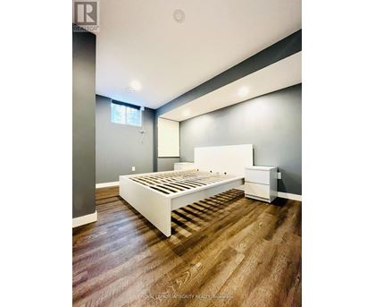A bedroom with a white bed and wooden flooring.