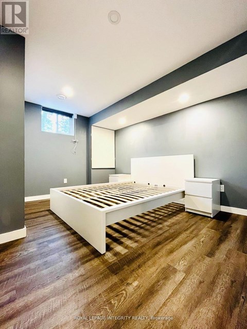 A bedroom with a white bed and wooden flooring.
