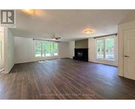 A spacious room with wooden flooring and a ceiling fan.