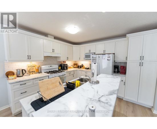 A kitchen with white cabinets and a marble countertop.