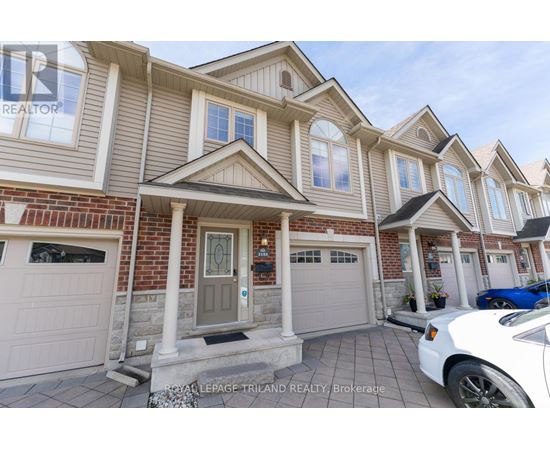A white car is parked in front of a house with a realtor sign.