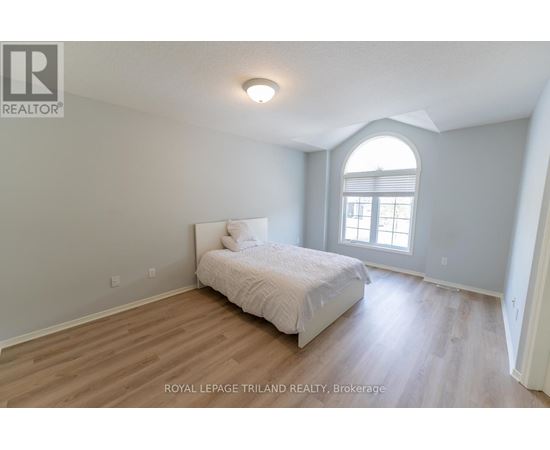 A bedroom with a bed, wooden floors, and a window.