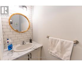 A white bathroom with a round mirror and a towel hanging on the towel rack.