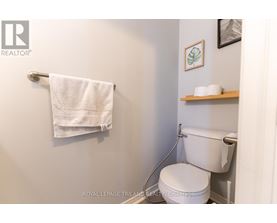 A white toilet in a small bathroom with a towel hanging on the wall.