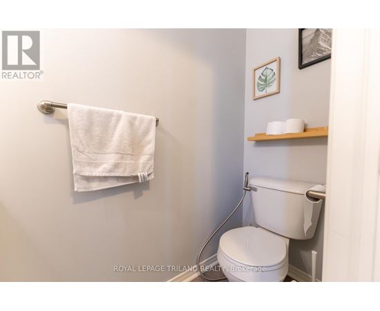 A white toilet in a small bathroom with a towel hanging on the wall.